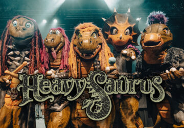 Wenn Sie an Heavy Metal denken, kommen Ihnen wahrscheinlich dröhnende Gitarren, donnernde Trommeln und wilder Gesang in den Sinn. Aber wenn Sie noch eine prähistorische Note hinzufügen, erhalten Sie Heavysaurus – eine deutsche Band, die die Welt mit ihrer einzigartigen Mischung aus Heavy Metal und Kinderunterhaltung im Sturm erobert hat. Mit einer Kombination aus Dinosaurierkostümen, eingängigen Melodien und familienfreundlichen Texten hat Heavysaurus eine Nische geschaffen, die sowohl Kinder als auch Erwachsene anspricht.