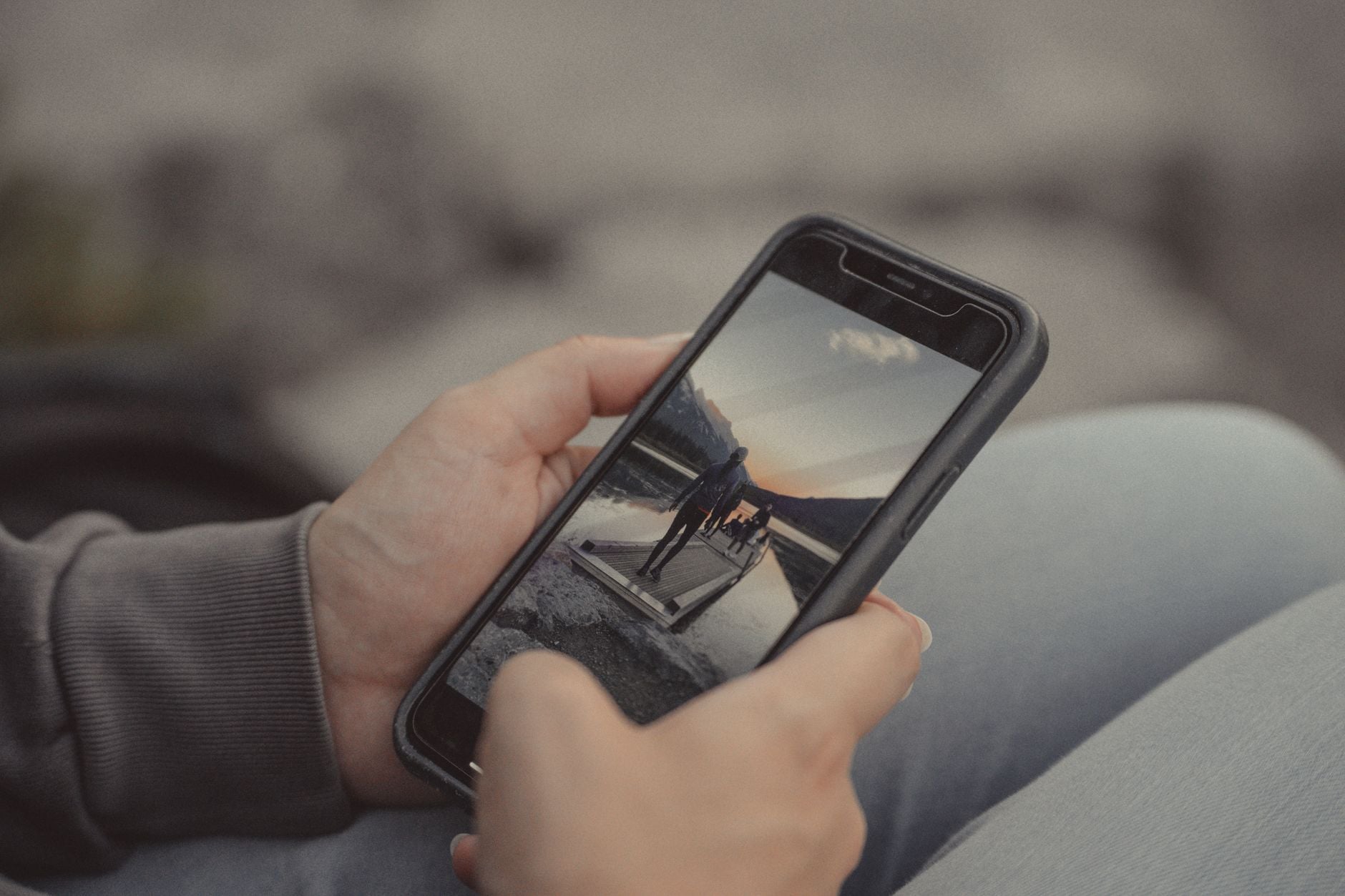 Persona che tiene uno smartphone con foto in bianco e nero di una montagna e persone sullo schermo
