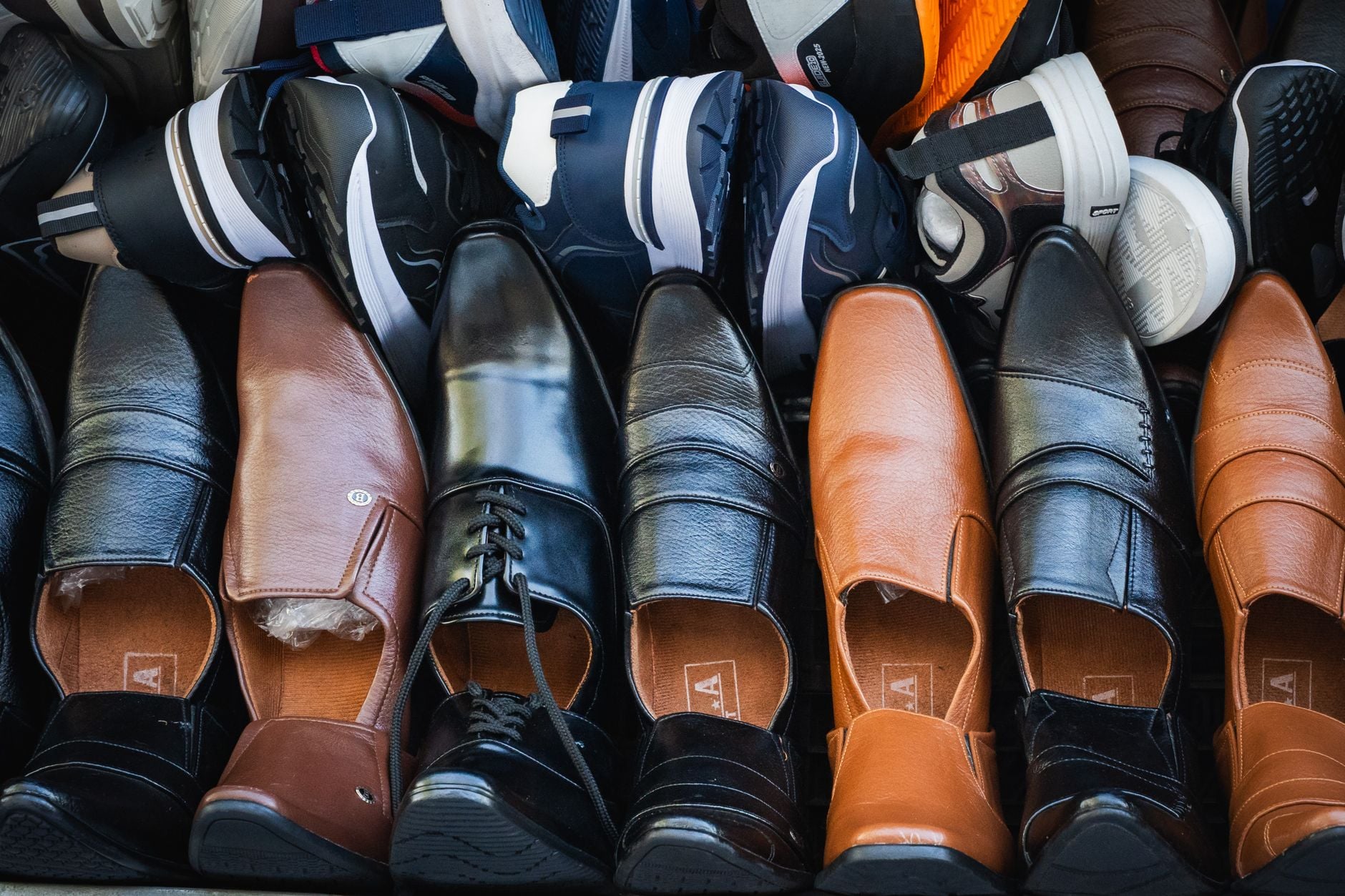 Scarpe da ginnastica e mocassini in pelle di vari colori esposti in negozio con calzini colorati