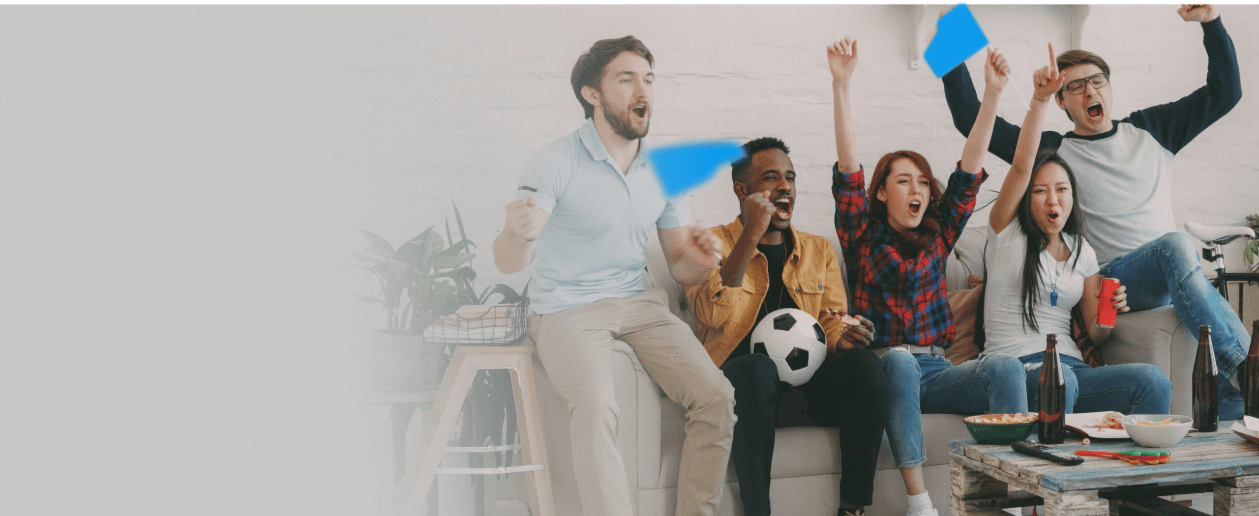Gruppo di persone sedute che guardano una partita di calcio e festeggiano insieme