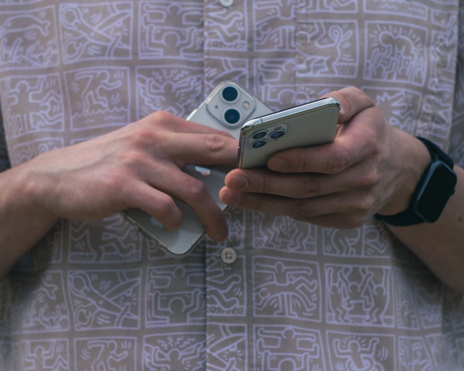 Due mani confrontano due smartphone con fotocamere doppie su sfondo con motivi geometrici astratti