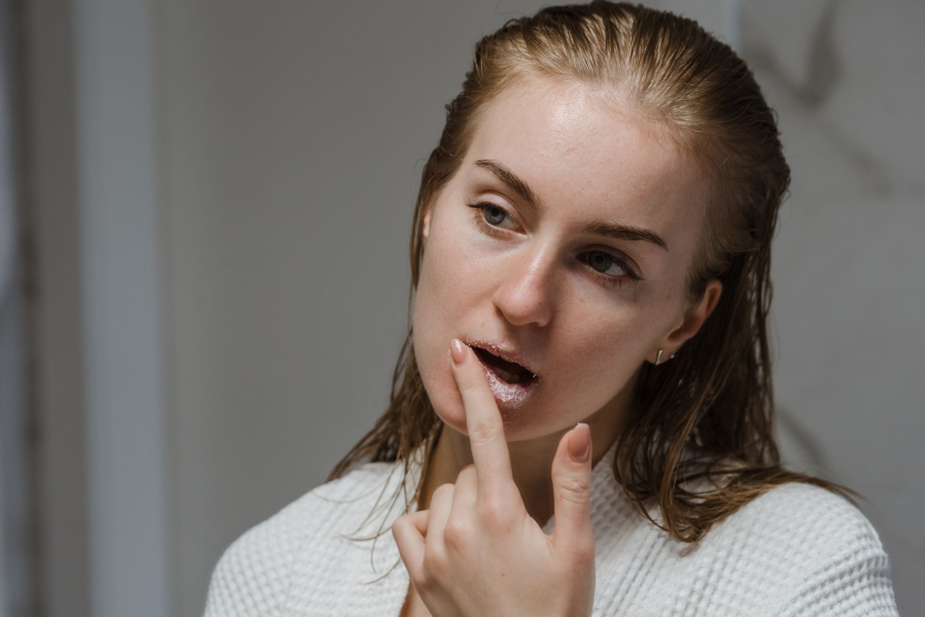 Donna con espressione sorpresa tocca il viso con il dito indice